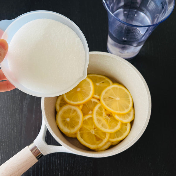 adding lemon slices and sugar to a small pot
