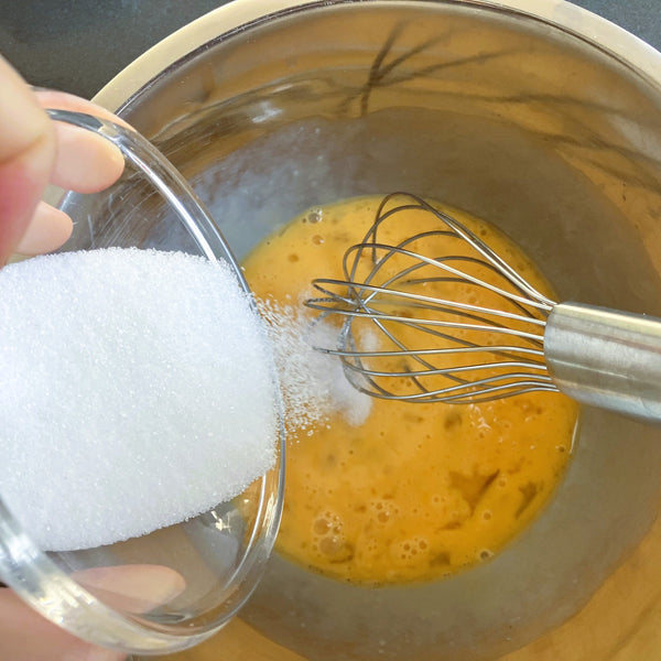 pouring the sugar into the beaten eggs