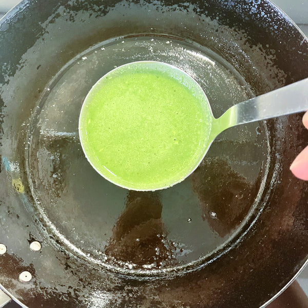 adding a ladle full of matcha crepe batter to the pan