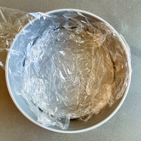 lining the cake pan with plastic wrap