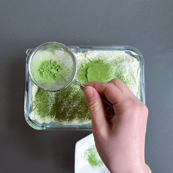 dusting matcha tiramisu with more matcha powder
