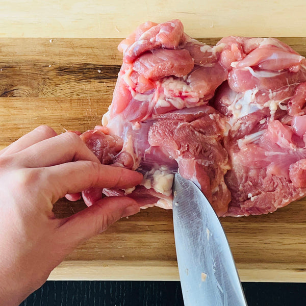 cutting excess fat off of the chicken